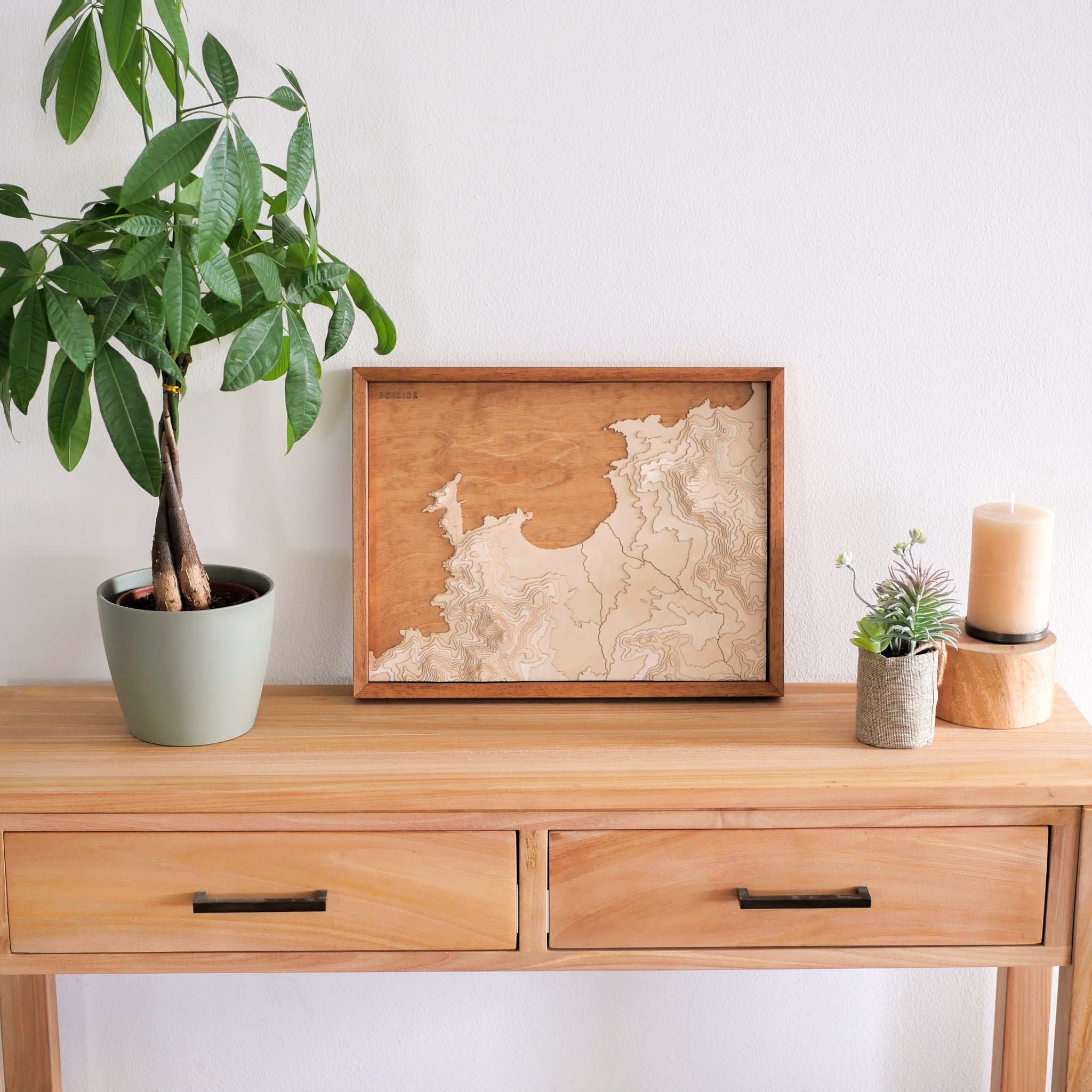 Décoration de l'entrée d'une maison corse avec un tableau de la baie de Calvi posé sur une commode en bois