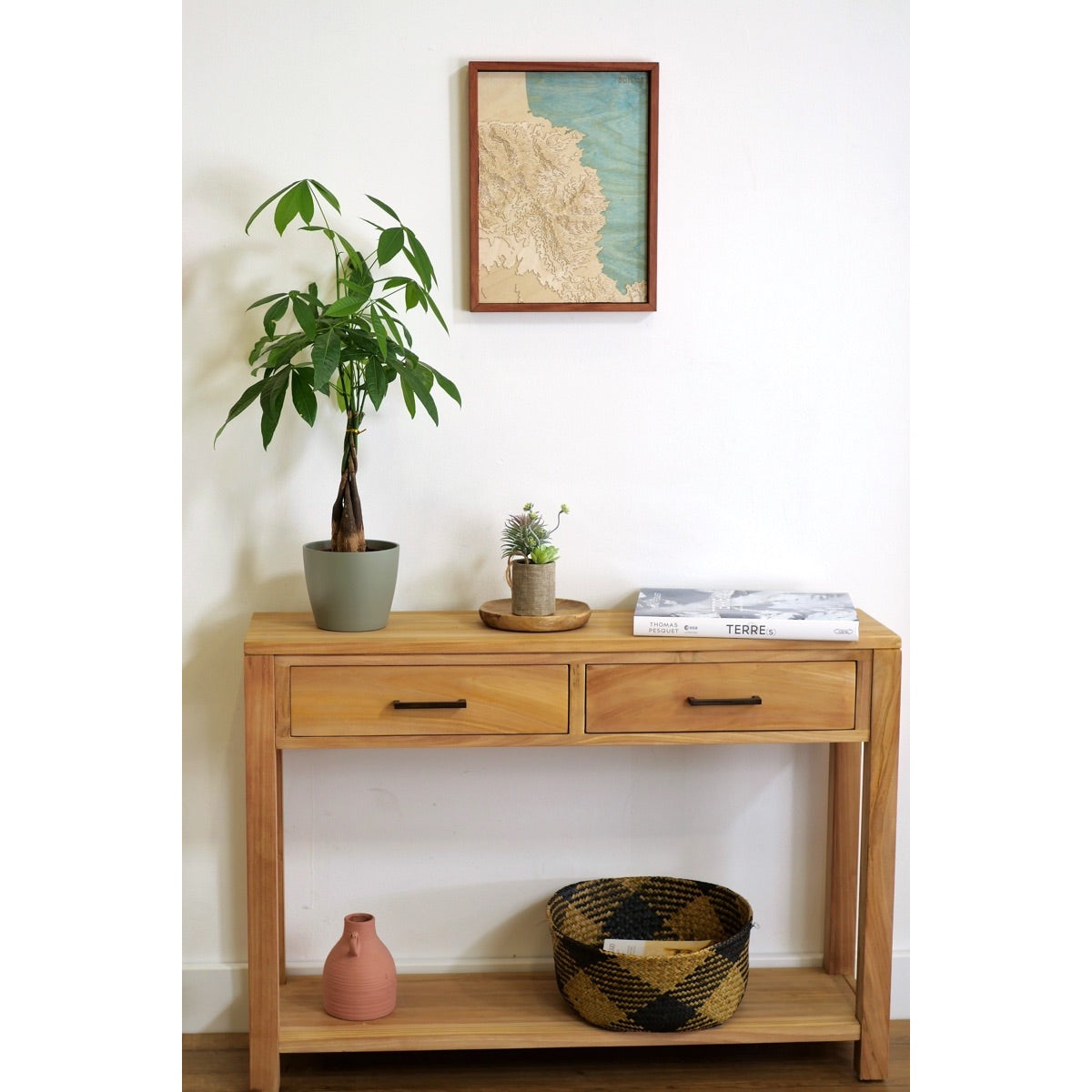 Entrée d'une maison catalane décorée en bois avec une commode et une carte de la côte vermeille en relief