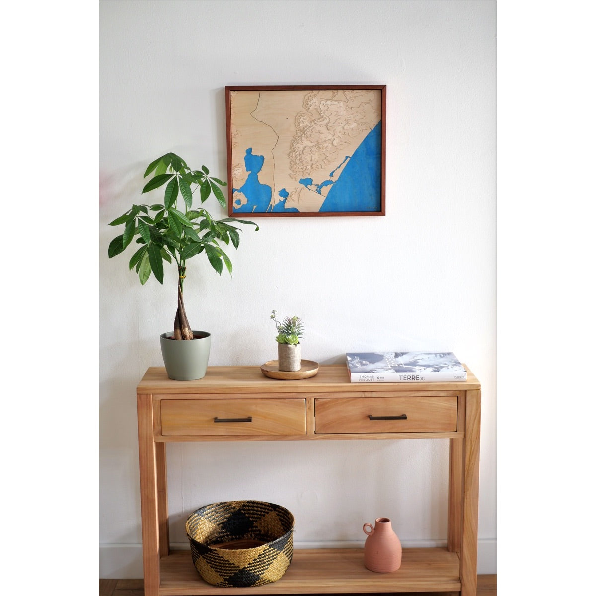 Entrée d'une maison audoise décorée avec une commode en bois et la carte en relief du massif de la Clape